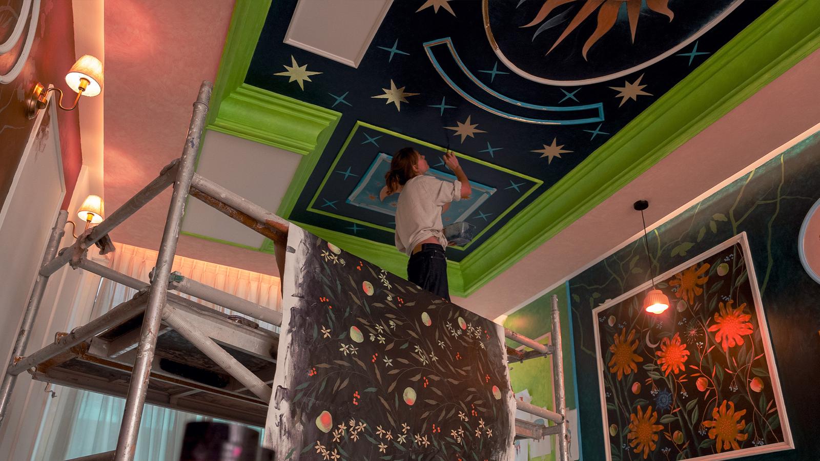 The finished celestial ceiling seen from the room below, with the artist on scaffolding